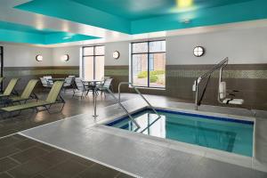 a pool in a hotel room with tables and chairs at Hampton Inn & Suites Syracuse North Airport Area in North Syracuse