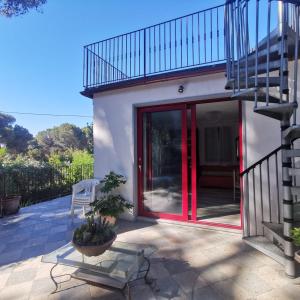 a house with a red door and a staircase at Casa Nel Verde Vista Mare in Quercianella +5 photos