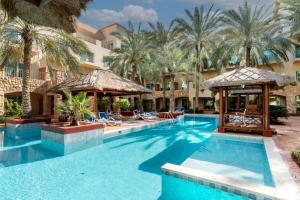 a pool at a resort with palm trees at Mövenpick Hotel & Resort Al Bida'a in Kuwait