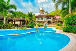 two people standing in a pool in front of a house at Coron Soleil Garden Resort in Coron