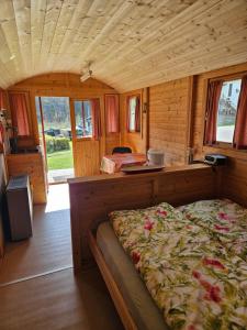 a bedroom with a bed in a wooden cabin at Camping La Hêtraie pipowagen in Bullange
