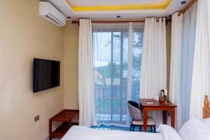 a bedroom with a bed and a desk and a window at Fortis Hill Hotel in Arusha