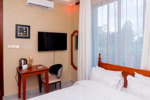 a bedroom with a bed and a desk and a television at Fortis Hill Hotel in Arusha