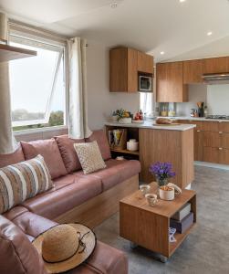 a living room with a brown couch and a kitchen at Camping Le Mas de Reilhe in Crespian