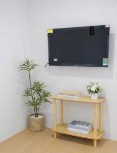 a tv on a wall with a table and a plant at Machy Home in Phú Quốc