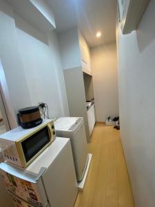 a small kitchen with a microwave on top of a refrigerator at Hotel MR TOMO ATAMI 102 in Atami