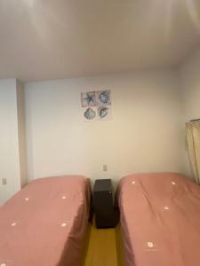 a bedroom with two beds and a wall with two pictures at Hotel MR TOMO ATAMI 102 in Atami