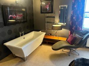 a bathroom with a large white tub and a chair at BAE SUITE 5 min walk to bae systems in Barrow in Furness