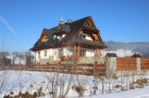 une maison dans la neige avec une clôture en bois dans l'établissement Willa Misiowa Chata, à Czarna Góra