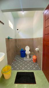 a bathroom with a toilet and a sink and buckets at Mango Lodge in Gili Gede