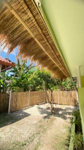 a large straw umbrella on a house with a fence at Mango Lodge in Gili Gede