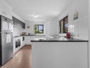 a large white kitchen with a black counter top at Riverstone Crescent Residence in Caloundra West