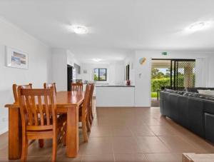 a kitchen and dining room with a wooden table and chairs at Riverstone Crescent Residence in Caloundra West
