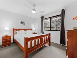 a bedroom with a wooden bed and a window at Riverstone Crescent Residence in Caloundra West +14 photos
