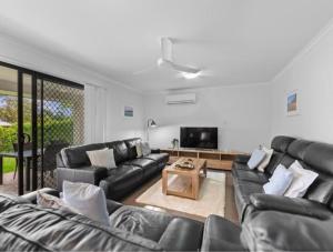 a living room with black leather furniture and a flat screen tv at Riverstone Crescent Residence in Caloundra West