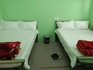 two twin beds in a room with towels on the floor at Cloud Hill Homestay in Jālāpahār +5 photos
