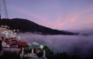 a view of a city in the fog at night at Cloud Hill Homestay in Jālāpahār