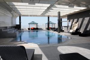 a swimming pool in a building with tables and chairs at Frsan Palace Hotel in Manama