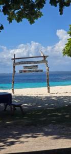 a bench on a beach with a sign on it at Pamilacan Vacay in Baclayon