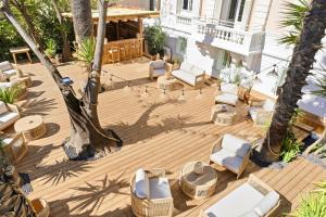 an outdoor deck with lounge chairs and palm trees at Villa Claudia Hotel Cannes Centre - Parking in Cannes