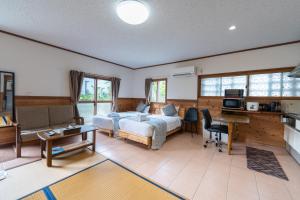 a bedroom with a bed and a desk and a kitchen at ヴィラ結Miyakojima2 in Miyako-jima