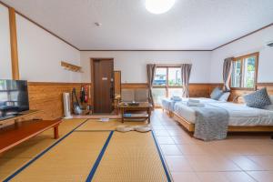 a bedroom with a large bed and a television at ヴィラ結Miyakojima2 in Miyako-jima