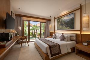 a bedroom with a large bed and a television at Anumana Ubud Hotel in Ubud
