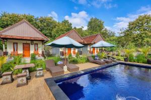 a villa with a swimming pool with chairs and umbrellas at Lungguh Penida Hut in Nusa Penida