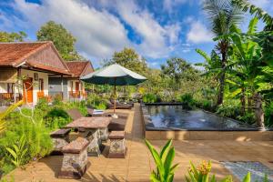 a patio with a table and an umbrella next to a pool at Lungguh Penida Hut in Nusa Penida