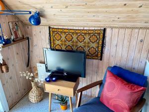a room with a tv and a chair and a table at Hedebo Strand Camping in Sæby