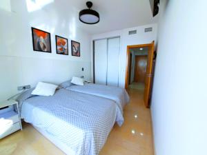 a white bedroom with two beds and a hallway at Coblanca 41-spectacular views-gym-heated pool-sauna-jacuzzi-wifi-3 minutes walk from the sear in Benidorm +53 photos