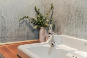 a white sink with a vase of flowers in a bathroom at The Barn Daylesford in Daylesford