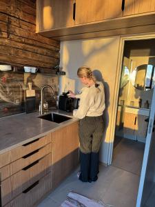 a woman standing in a kitchen next to a sink at Apartment at NerSalberg Farm in Røra, Inderøy in Røra +12 photos