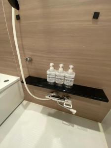 a bathroom with three bottles on a shelf next to a toilet at Hotel MR TOMO ATAMI 301 in Atami