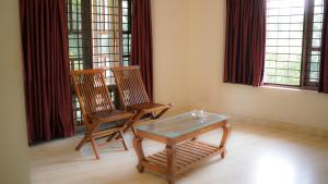 two chairs and a table in a room with windows at Haven Grace in Kovalam