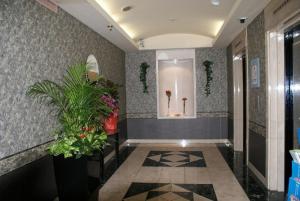 a lobby with a hallway with flowers and plants at Urban Hotel Twins Chofu in Chofu