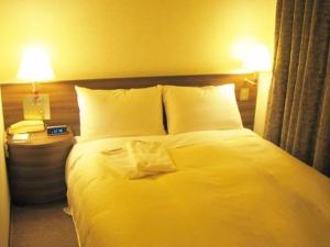 a bedroom with a large white bed with two lamps at Urban Hotel Twins Chofu in Chofu