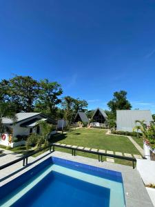 a swimming pool in front of a house with a yard at Paraiso Del Bacnotan in Bacnotan