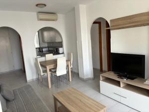 a living room with a television and a table with chairs at Apartamentos Torrelaguna in Vera
