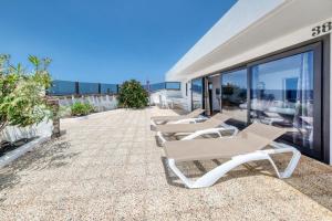 a row of lounge chairs on a patio with the ocean at Bungalow Olas del Risco - Ocean views - Beach 2 min By Lanzarote Vacation Homes in Famara
