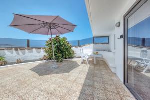 a patio with an umbrella and a table at Bungalow Olas del Risco - Ocean views - Beach 2 min By Lanzarote Vacation Homes in Famara