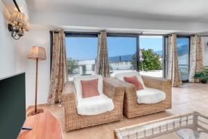 a living room with a table and chairs and windows at Bungalow Olas del Risco - Ocean views - Beach 2 min By Lanzarote Vacation Homes in Famara