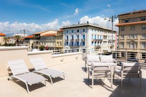 a group of white chairs on a balcony with buildings at Casa OliVera in Viareggio