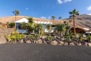 a house with palm trees and a rock wall at Villa Liquen in Yaiza