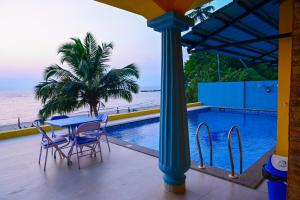 a patio with a table and chairs next to a pool at Serenity by the Sea Goa in Silidao