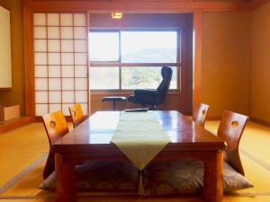 uma mesa e cadeiras num quarto com uma janela em Hoshi Meguri em Shimoda