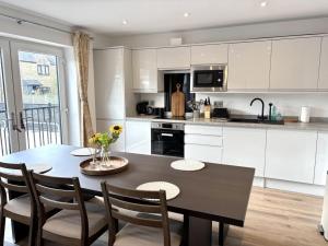 a kitchen with a table and chairs and a kitchen with white cabinets at Smithy Mills in Halifax