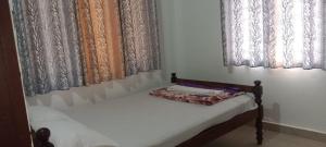 a small bed in a room with windows at Wind Bells in Anaviratty