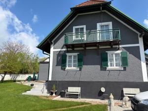 a gray house with green shutters and a balcony at Haus Erika in Gamlitz