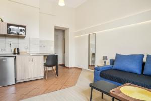 a living room with a blue couch and a kitchen at Apartament Pierwszy Maj in Kudowa-Zdrój